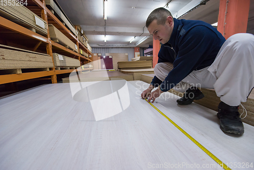 Image of carpenter measuring wooden board