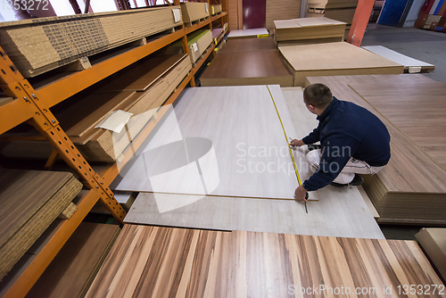 Image of carpenter measuring wooden board
