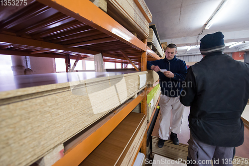 Image of two young carpenters working in big modern carpentry