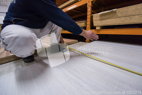 Image of carpenter measuring wooden board