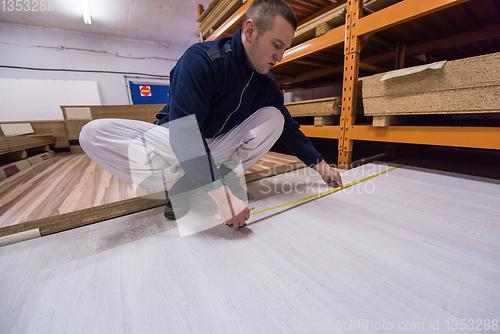 Image of carpenter measuring wooden board