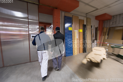 Image of two young carpenters working in big modern carpentry