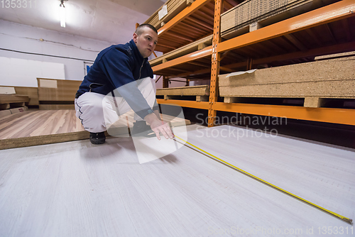 Image of carpenter measuring wooden board