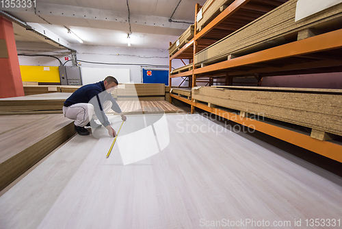 Image of carpenter measuring wooden board