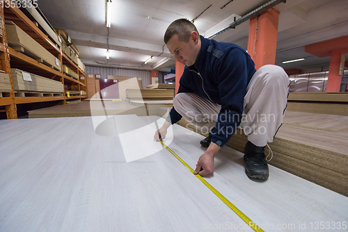 Image of carpenter measuring wooden board