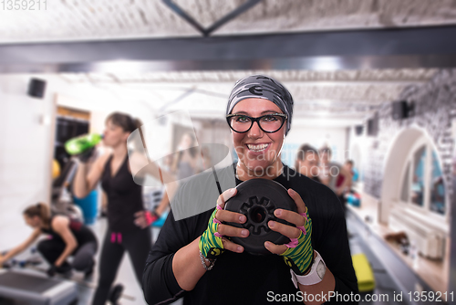 Image of sporty woman holding a metal round weights plate