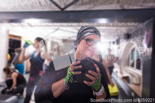 Image of sporty woman holding a metal round weights plate