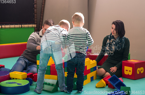 Image of young parents and kids having fun at childrens playroom