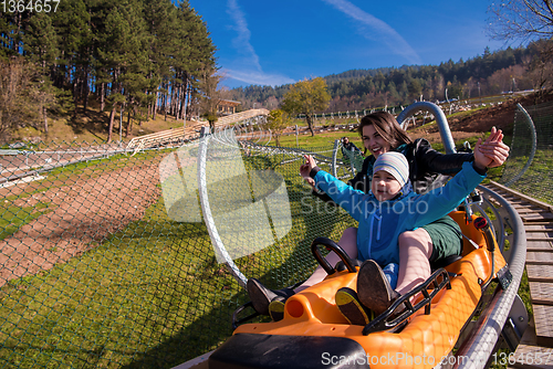 Image of young mother and son driving alpine coaster