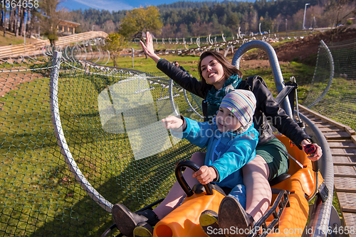 Image of young mother and son driving alpine coaster