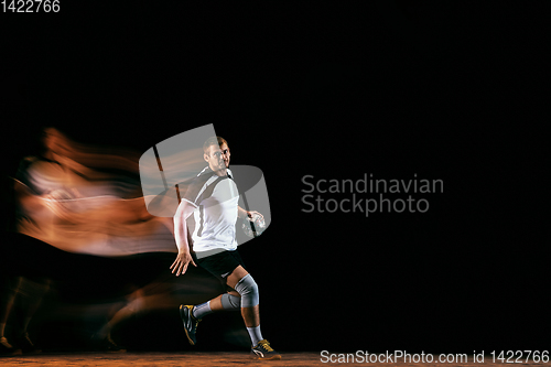 Image of Young handball player against dark studio background in mixed light