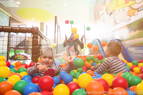 Image of young mom playing with kids in pool with colorful balls