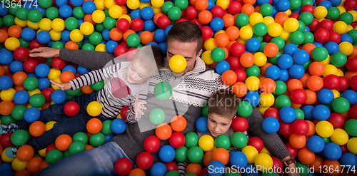 Image of dad and kids playing in pool with colorful balls