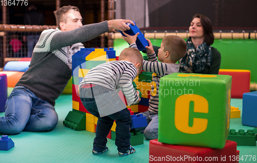 Image of young parents and kids having fun at childrens playroom