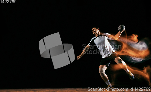 Image of Young handball player against dark studio background in mixed light