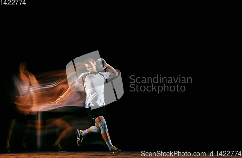 Image of Young handball player against dark studio background in mixed light