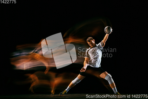 Image of Young handball player against dark studio background in mixed light