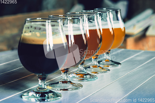 Image of Glasses of different kinds of beer on wooden background