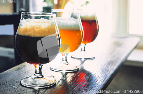 Image of Glasses of different kinds of beer on wooden background