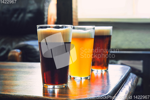 Image of Glasses of different kinds of beer on wooden background