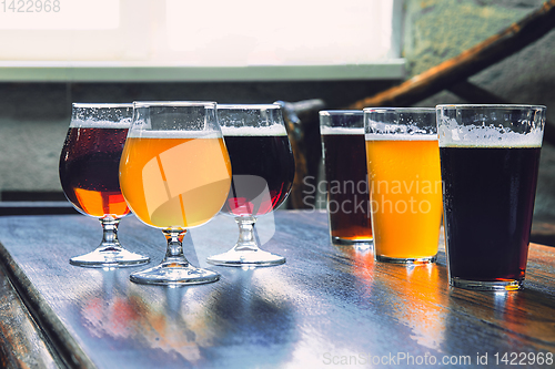 Image of Glasses of different kinds of beer on wooden background