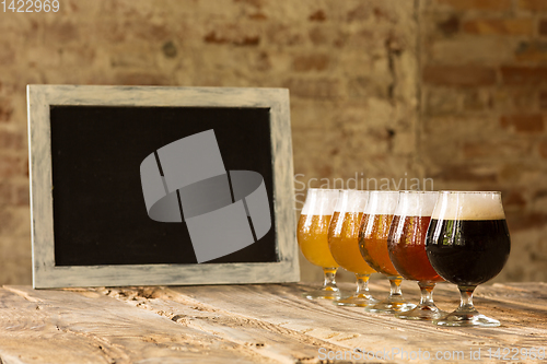 Image of Glasses of different kinds of beer on wooden background