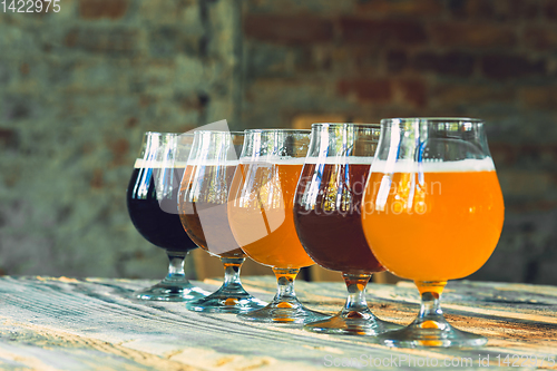 Image of Glasses of different kinds of beer on wooden background