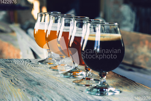 Image of Glasses of different kinds of beer on wooden background