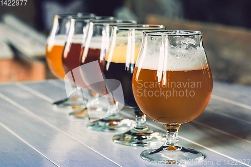 Image of Glasses of different kinds of beer on wooden background