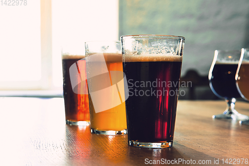 Image of Glasses of different kinds of beer on wooden background