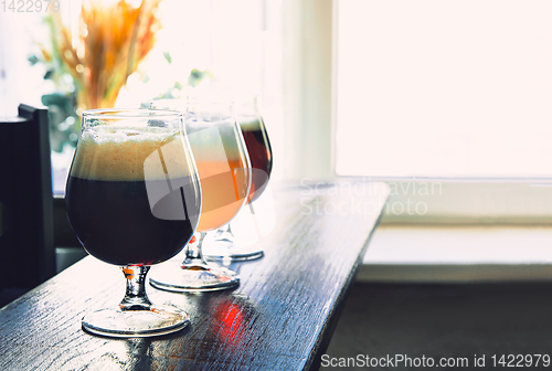 Image of Glasses of different kinds of beer on wooden background