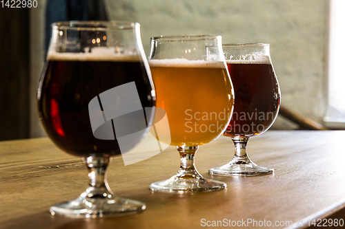 Image of Glasses of different kinds of beer on wooden background