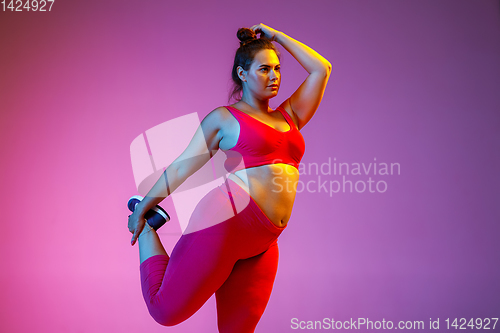 Image of Young caucasian plus size female model\'s training on gradient background