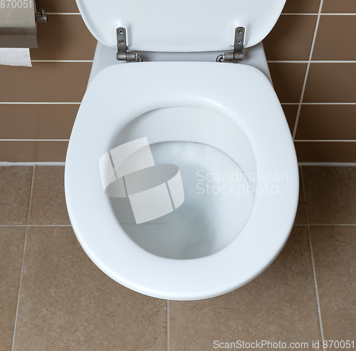 Image of White toilet bowl in the bathroom, flushing