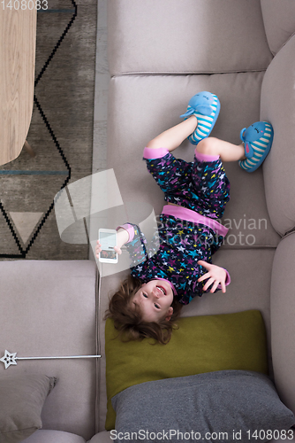 Image of top view of little girl using a smartphone on the sofa