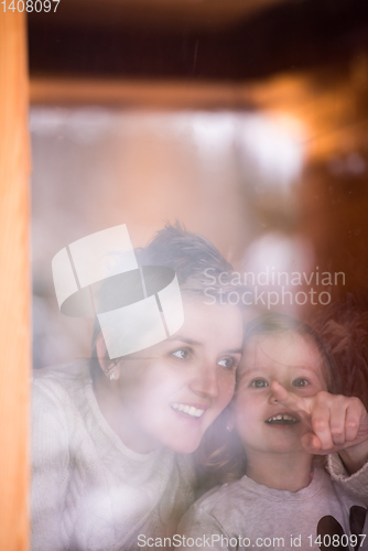 Image of young mother and little cute daughter playing near the window