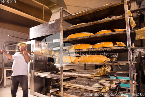 Image of bakery worker taking out freshly baked breads