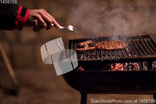 Image of young man cooking meat on barbecue