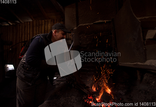 Image of young traditional Blacksmith working with open fire