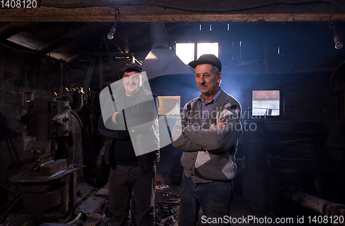Image of portrait of two generations confident blacksmith