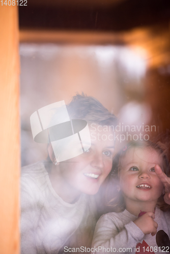 Image of young mother and little cute daughter playing near the window