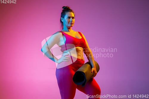 Image of Young caucasian plus size female model\'s training on gradient background
