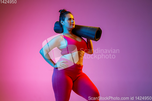 Image of Young caucasian plus size female model\'s training on gradient background