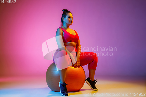 Image of Young caucasian plus size female model\'s training on gradient background