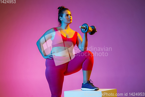 Image of Young caucasian plus size female model\'s training on gradient background