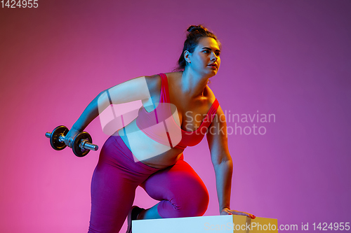 Image of Young caucasian plus size female model\'s training on gradient background