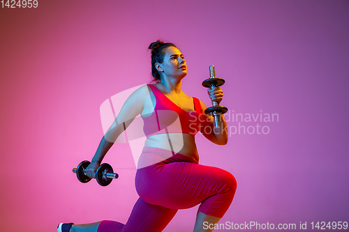 Image of Young caucasian plus size female model\'s training on gradient background