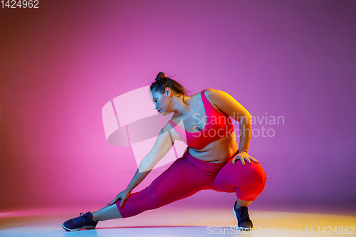 Image of Young caucasian plus size female model\'s training on gradient background