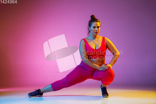 Image of Young caucasian plus size female model\'s training on gradient background