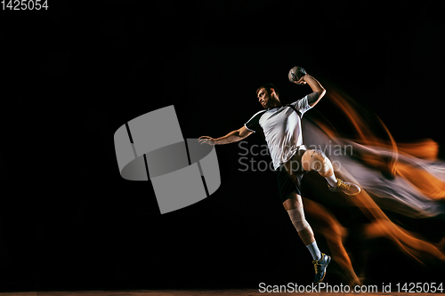 Image of Young handball player against dark studio background in mixed light